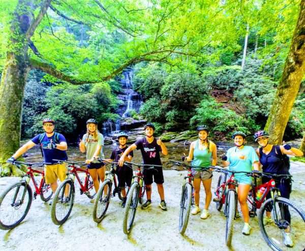 A group of people on mountain bikes pose for the camera in the forest.
