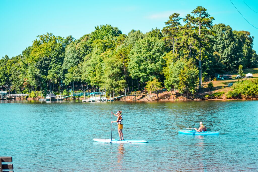 A paddle boarder and kayaker explore the water near Mountain Island Lake.